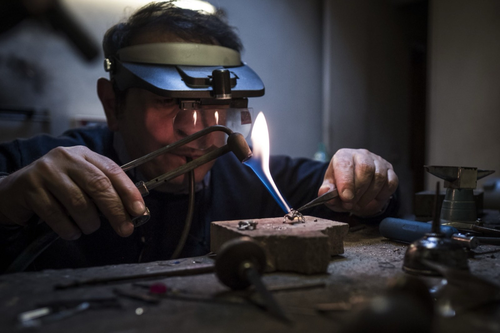 A goldsmith soldering a piece by flame at the Gisci workbench